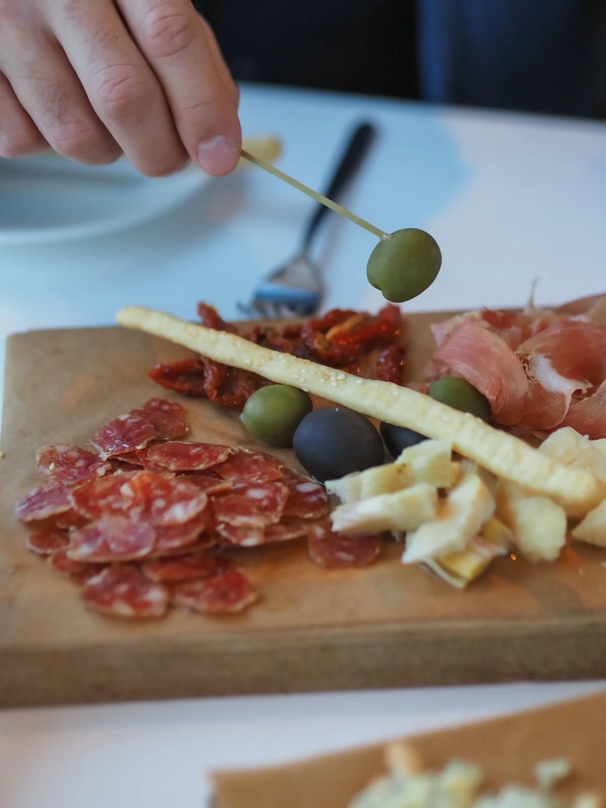 Włoskie aperitivo – deska antipasti z zielonymi oliwkami, salami, serem i grissini